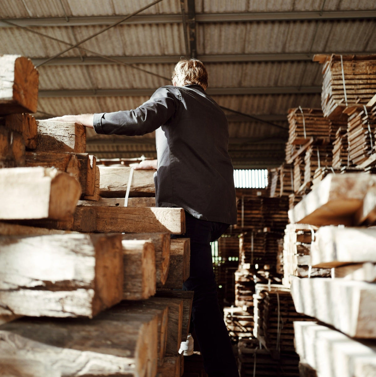 Person inspecting reclaimed French oak beams in a warehouse