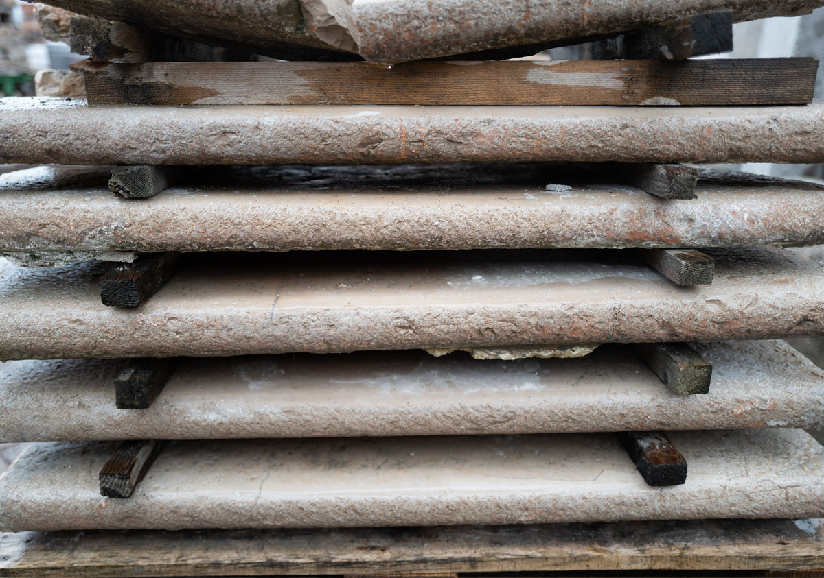 Stacked reclaimed Basilica Italian limestone slabs showing worn edges