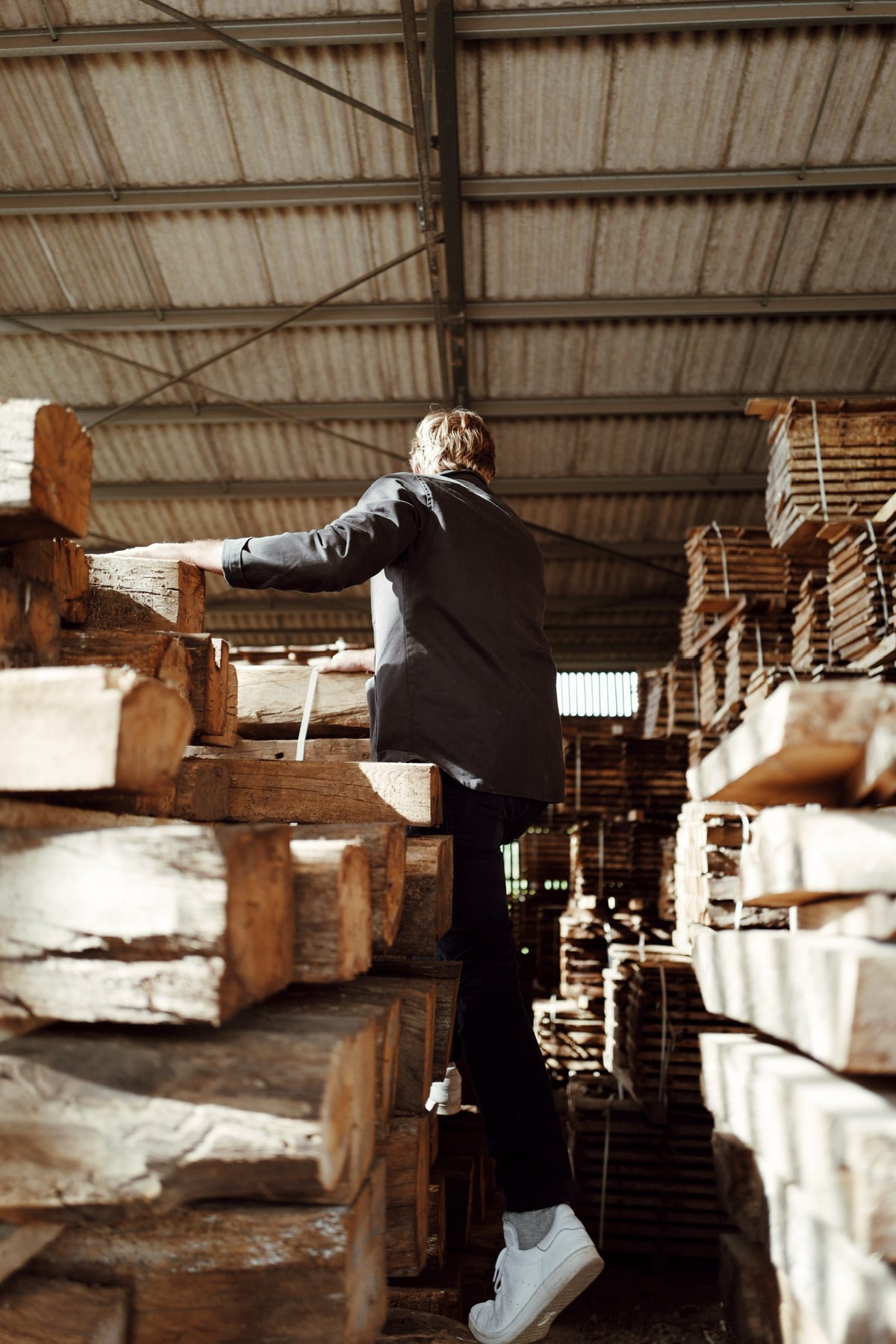 Person inspecting reclaimed French oak beams in a warehouse