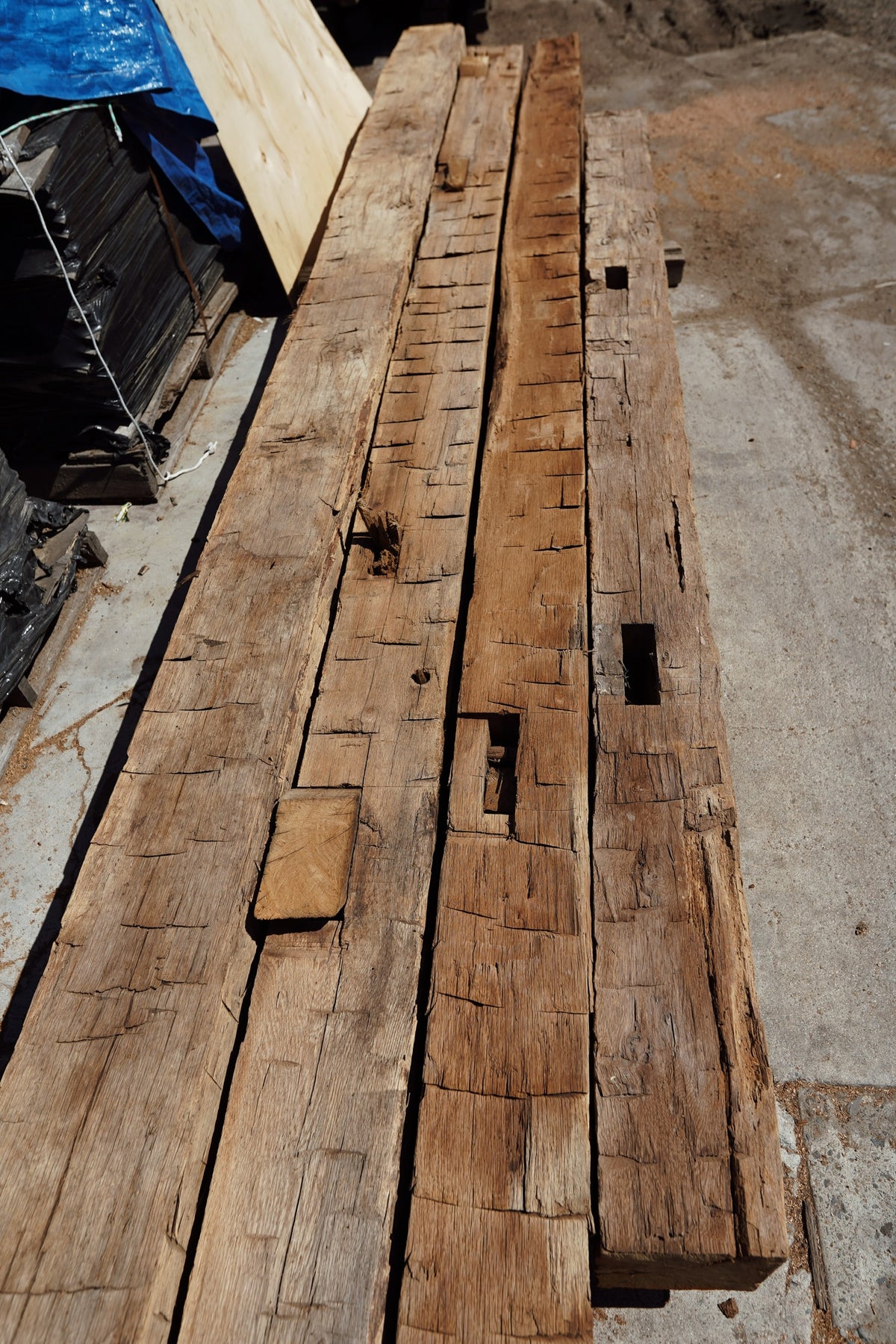 Hand hewn reclaimed oak beams laid out showing axe marks and mortises